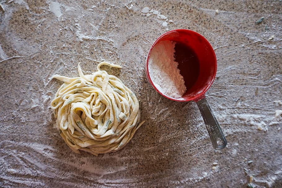 freshly made pasta noodles and cup of flour