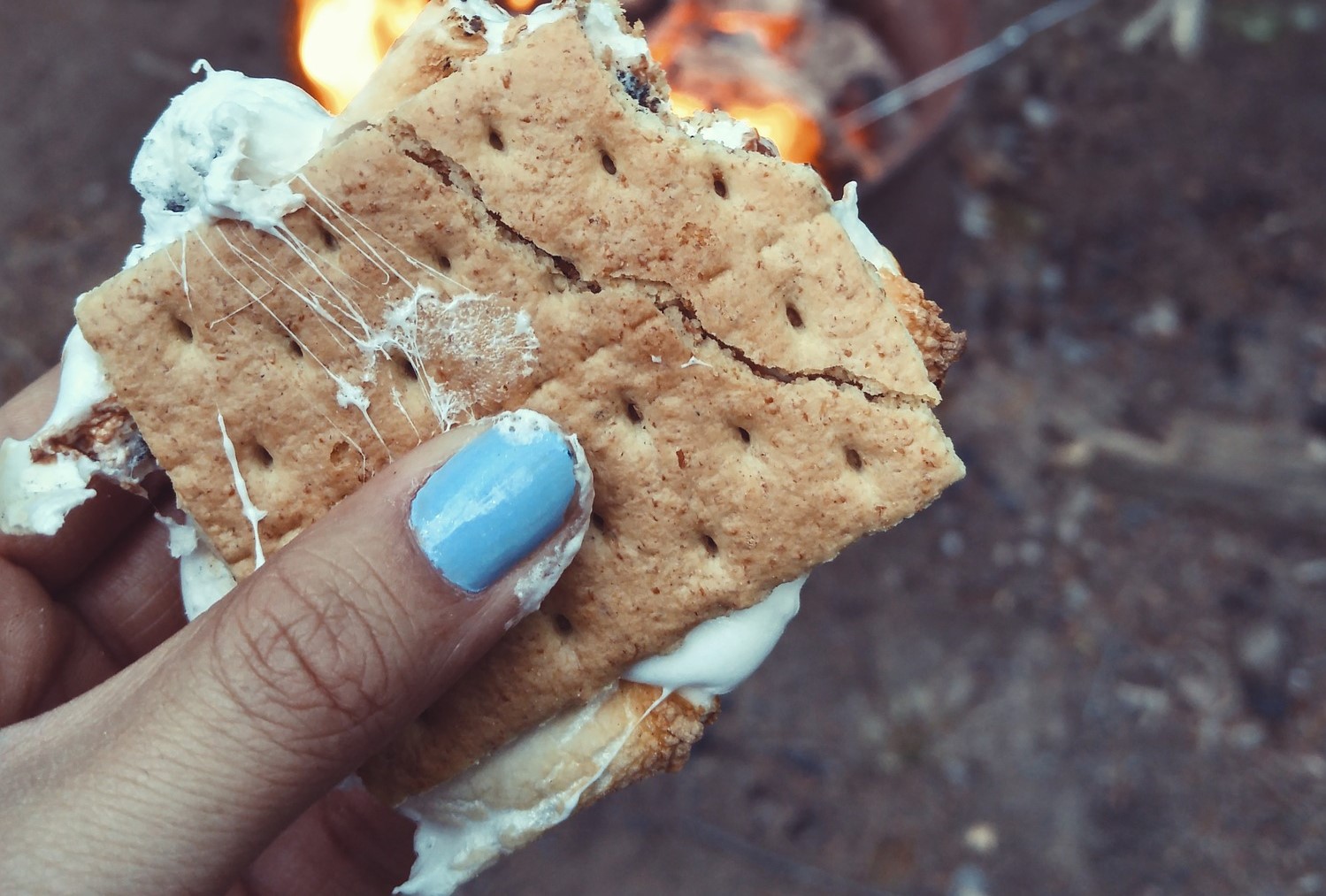 person with nail polish holding a smore