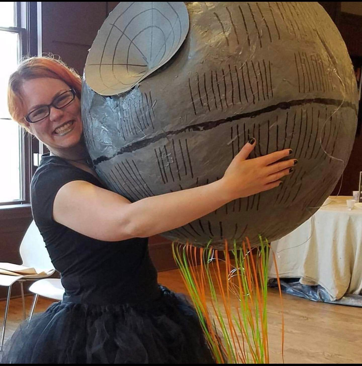 Person in a tutu hugging a model of the Star Wars Death Star