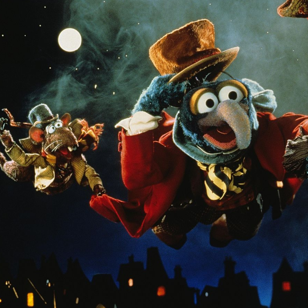 Gonzo wearing a top hat and a dress jacket flying through the air hanging on to the paw of Rizzo.