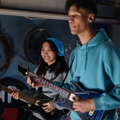 two teen kids hold video game guitars playing guitar hero