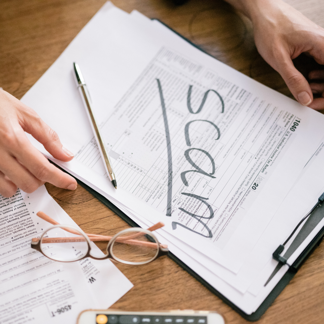 scam written on fraudulent tax forms with hands glasses and pen