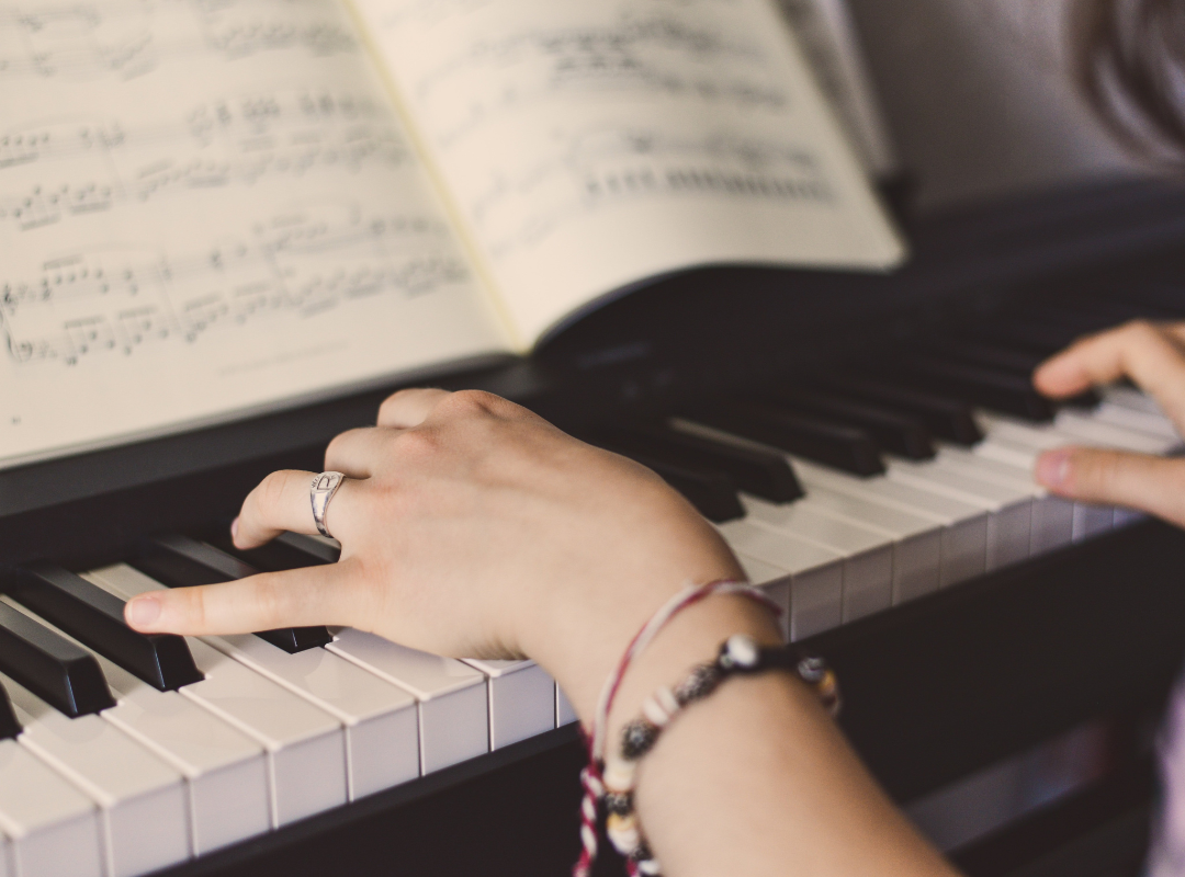 hands resting on piano keys with sheet music